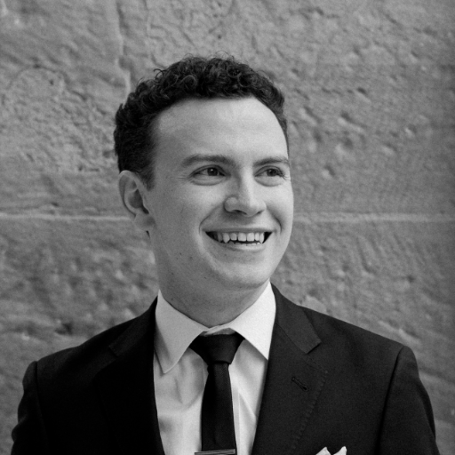 A greyscale photo of Liam, looking to the right and smiling.